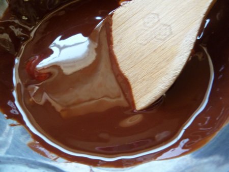 始めに、型にバターを塗り準備します。次に板チョコを湯せんで溶かし、細かく切ったバターを加えさらに溶かします。